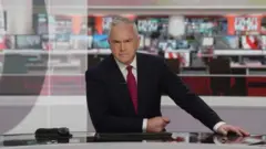 Huw Edwards em bancada de telejornal