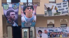 Casa com dois andares repleta de cartazes pendurados homenageando Messi e Maradona