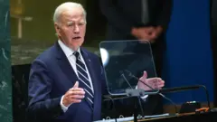 Presidente dos Estados Unidos, Joe Biden, em discurso na Assembleia Geral da ONU; ele veste terno azul escuro e gravata azul-escura com listras brancas