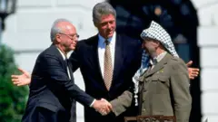 O aperto de mão entre Yitzhak Rabin e Yasir Arafat em frente a Bill Clinton.