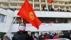 A woman holds the national flag as supporters of Kyrgyzstan"s Prime Minister Sadyr Japarov attend a rally in Bishkek, Kyrgyzstan October 15, 2020.