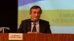 Antonio Cícero sentado à mesa durante palestra