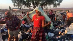 Mulher cobre cabeça com pano em lixão