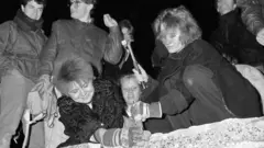 Berliners take a hammer and chisel to a section of the Berlin Wall in front of the Brandenburg Gate after the opening of the East German border was announced in Berlin on 9 November 1989