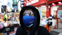 A man wear mask to prevent the coronavirus (COVID-19) walk along the Myungdong shopping district on February 23, 2020