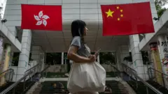 一名女子走過香港特區和中國國旗前