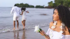 Pessoas pulando onda e depositando flores na praia vestidas de branco