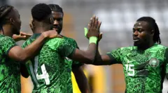 Moses Simon, vêtu d’un maillot vert du Nigeria avec le numéro 15 dessus, est photographié en train de donner un high five à son coéquipier Kelechi Iheanacho alors que les Super Eagles célèbrent un but.