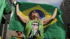 Mulher com blusa com rosto de Bolsonaro e ergue bandeira do Brasil 