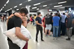 Homem abraça mulher em aeroporto de Confins