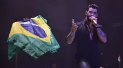 Cantor Gusttavo Lima ao lado de bandeira do Brasil durante show