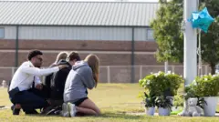 Grupo de estudantes em vigília improvisada do lado de fora da escola.