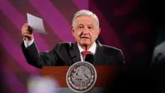 Andrés Manuel López Obrador, de terno e gravata vermelha, discursa com papel na mão 