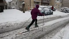 covek se na skijama probija kroz ulice beograda, sneg pada