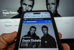 Tela de celular e de computador com venda online de show do Oasis