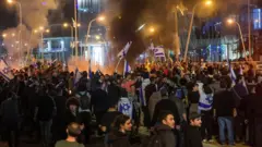 Manifestantes com bandeiras de Israel na rua à noite