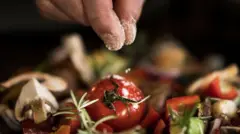 Close up of hand adding salt to a salad