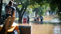 Pessoas carregam sacolas pelas ruas alagadas de Porto Alegre