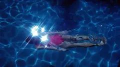 Pessoa nadando de maiô rosa neon em piscina