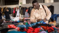 Un homme choisissant des vêtements dans une friperie