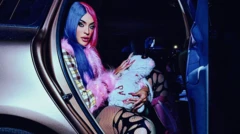 Pabllo Vittar com o cabelo pintado com duas cores diferentes sentada no banco de trás de carro