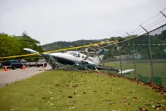 Fotografia de avião caido em cima de uma cerca