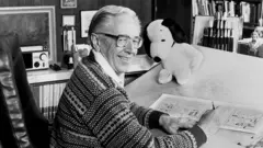 Charles M. Schulz em foto em preto e branco desenhando quadrinhos