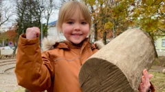 Menina segurando um tronco de árvore