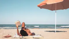 mulher deitada lendo na praia