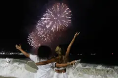 Casal de costas vendo fogos de artifícios na praia de Copacabana 