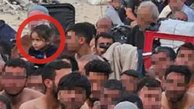 A zoomed-in image shows a group of Gazan men, in Israeli detention and sitting outdoors against the backdrop of a destroyed building. A little girl is there, circled in red by the BBC in this image, for clarity.