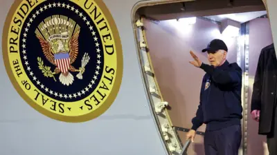 Joe Biden acena de dentro de avião