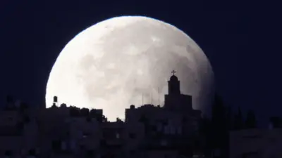 A supermoon with a partial lunar eclipse sets over the old city of Jerusalem, 18 September 2024.