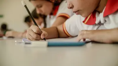 Crianças escrevendo numa sala de aula 