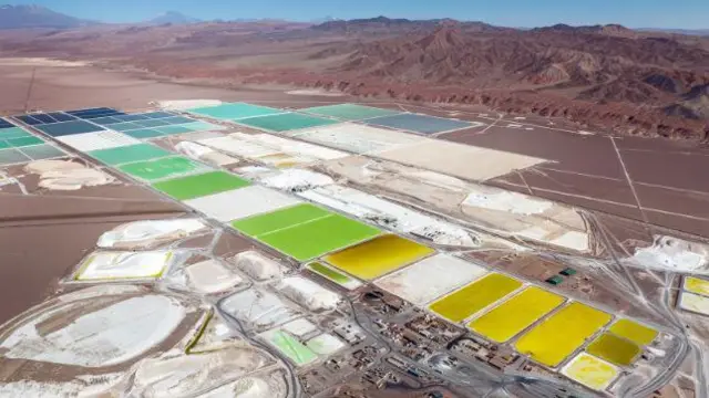 Foto aérea mostra grandes áreas com colorações amarelas, verdes e azuis, parte do processo de extração de lítio