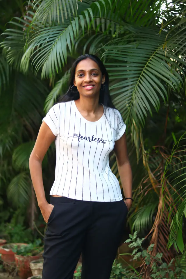 Pallavi debout près d'un arbre avec un t-shirt portant l'inscription "fearless" (sans peur).