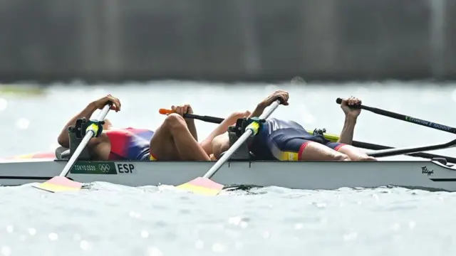 Dois remadores deitados para trás no barco, parecendo exaustos depois de terminar uma corrida