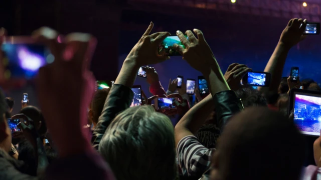 Várias pessoas com celular erguido em direção ao palco em show