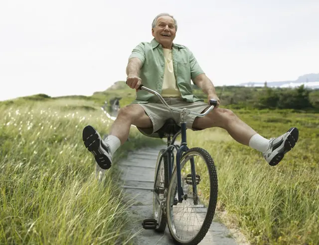 Homem com cabelos brancos anda de bicicleta animado