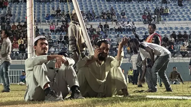 Migrantes esperando o início do jogo na fan zone do Asian Town