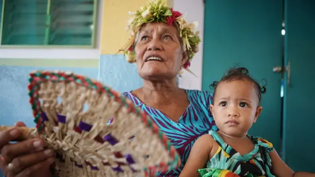 Mulher com uma menina nos braços em Tuvalu