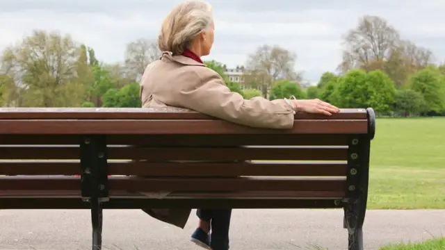 Mulher sentada sozinha num banco de praça