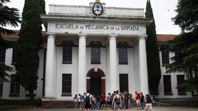 Fachada de prédio histórico, com visitantes caminhando em sua direção