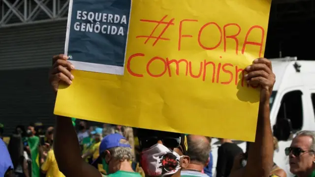 Manifestante em SP com cartaz em que se lê: "fora comunismo" e "esquerda genocida"