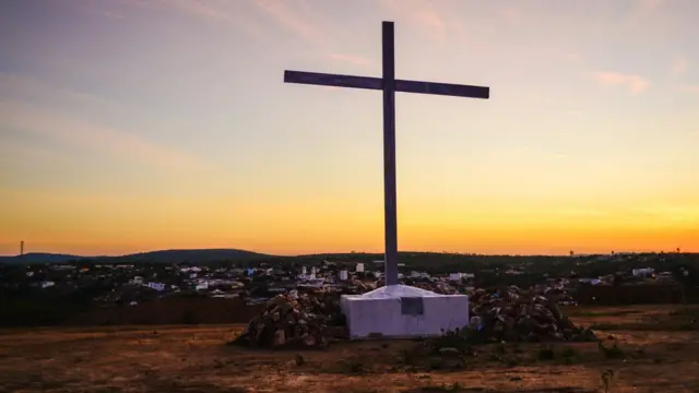 Cruz com vista de cidade do fundo