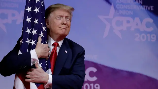 Donald Trump abraça a bandeira americana na reunião anual da CPAC, perto de Washington