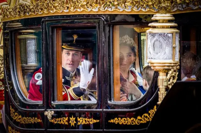 William acena para o público de dentro de carruagem