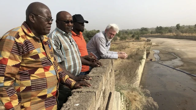 homens apoiados em muro em Gana