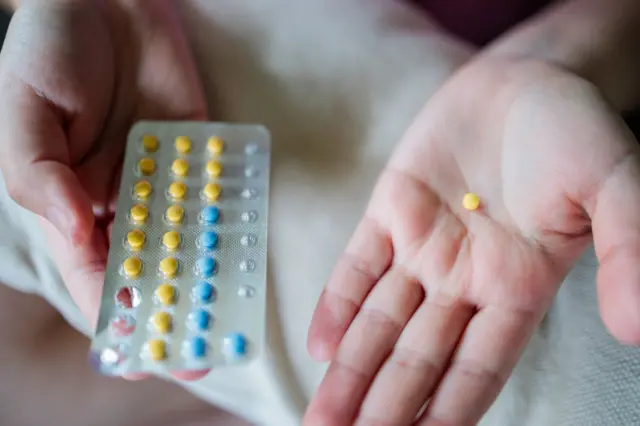 Mãos segurando cartela com pílulas