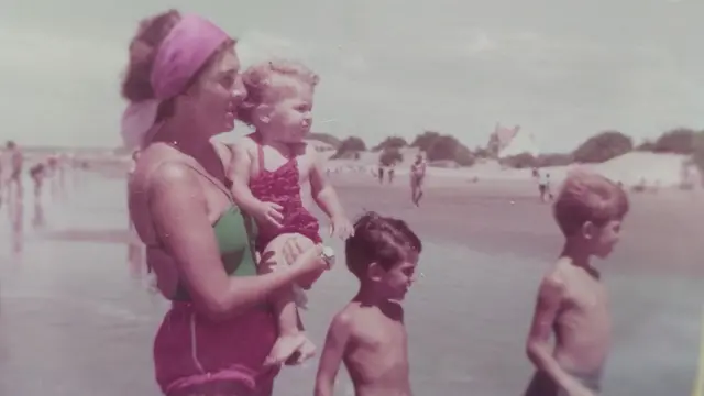 Candelaria bebê nos braços da sua mãe numa praia, em foto antiga